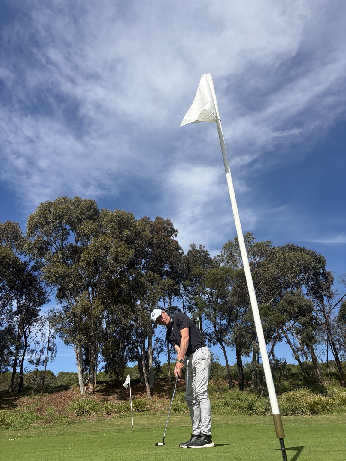 Matthew Davis practising a putt beside the flag in Heatherton